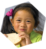 Smiling girl eating a peanut butter sandwich