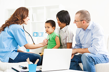 Female doctor listening to child's heart, with mom and dad providing support.